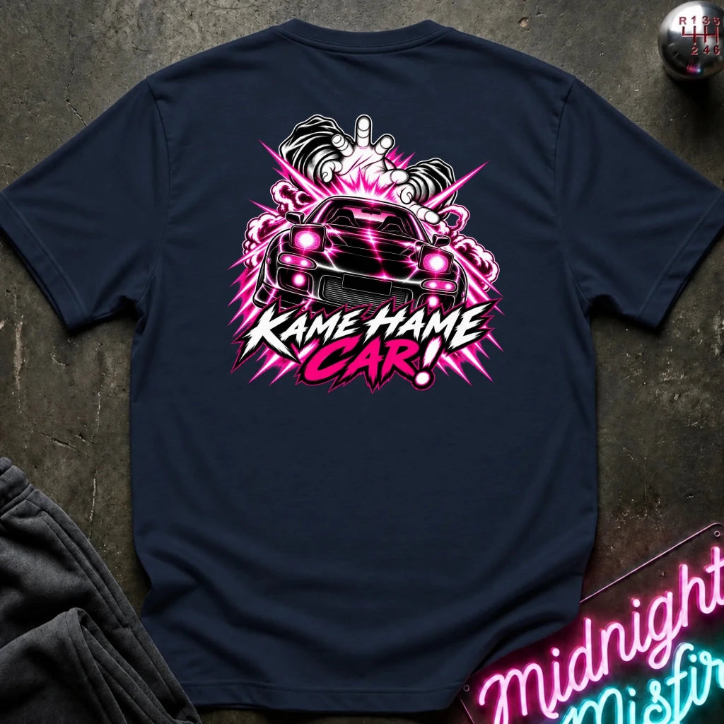 A navy blue t-shirt laid flat on a dark textured surface, featuring a large graphic on the back with a black car, pink and white smoke effects, and the text 'KAME HAME CAR!'.