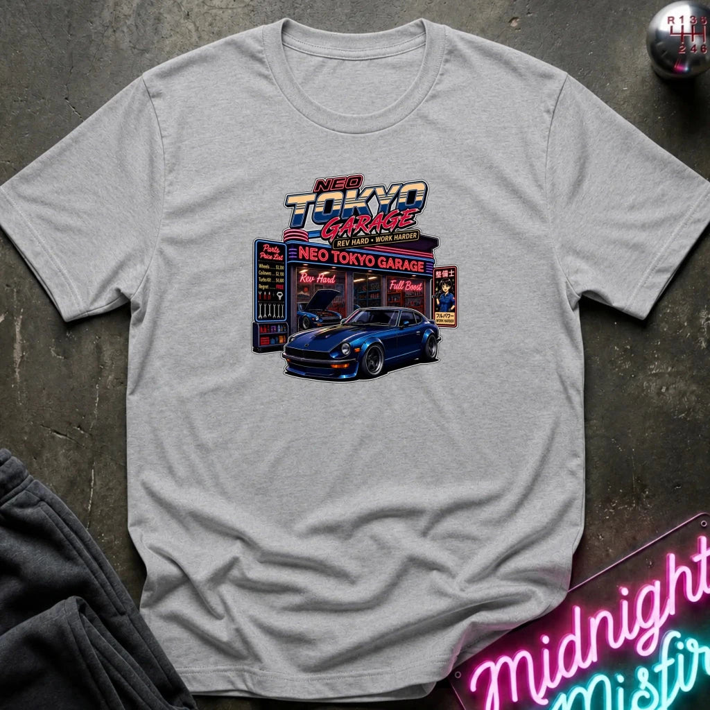 A light gray heather crewneck t-shirt featuring a colorful graphic print of a blue sports car in front of a neon 'Neo Tokyo Garage' sign. 