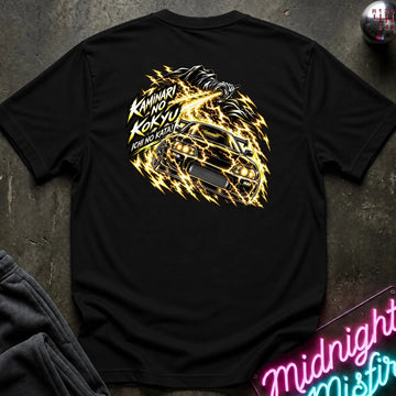 black short-sleeve t-shirt laid flat on a dark textured surface, showing the back graphic with a car and the text "ichi no kata!"
