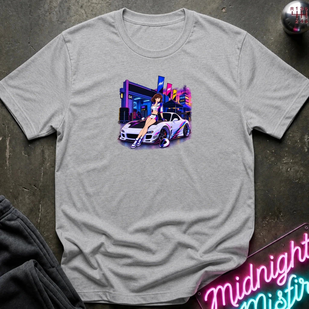 A light gray heather  short-sleeve t-shirt laid flat on a dark textured surface, featuring a colorful graphic print of a white sports car and a woman in a neon-lit scene. 