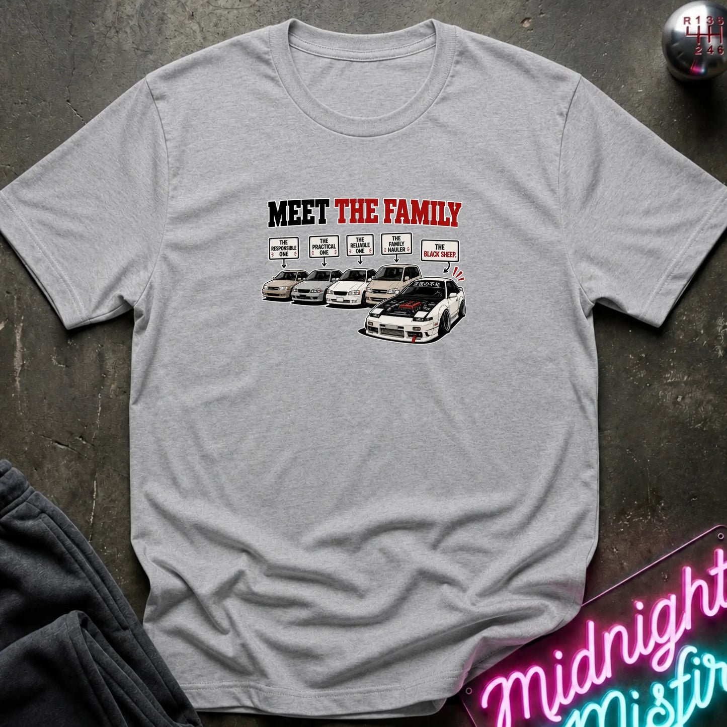 A gray short-sleeved t-shirt  that has a cars parked with one standing out that says black sheep.