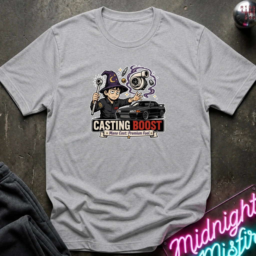 A light gray heather crewneck t-shirt featuring a colorful graphic of a cartoon wizard holding a wand next to a black car, with the text 'CASTING BOOST' 