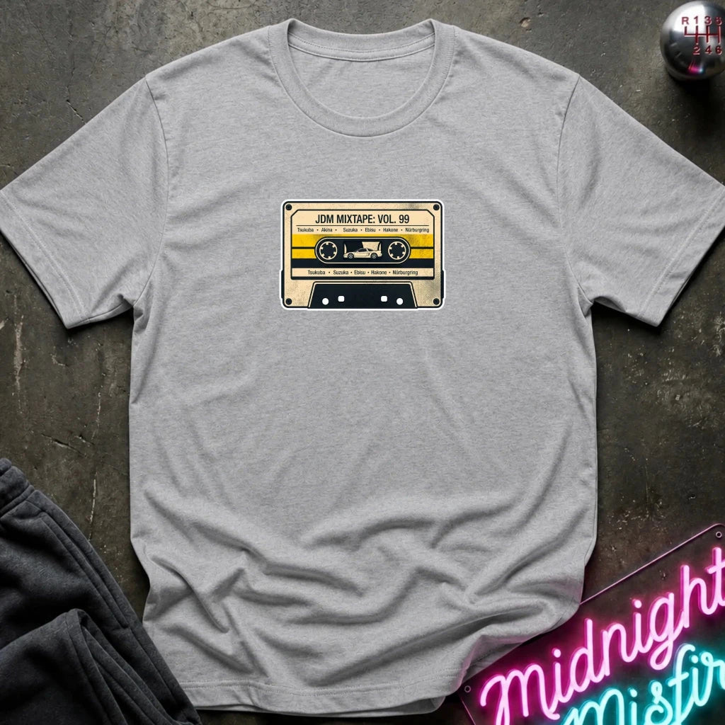 heather grey crewneck t-shirt laid flat on a dark textured surface, featuring a retro cassette tape graphic on the chest with the text 'JDM MIXTAPE VOL.