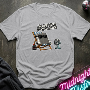 A light gray crewneck t-shirt laid flat on a dark textured surface, featuring a graphic of a intercooler with sunglasses, a cooler, and a fan beneath the text 'I'M JUST HERE TO COOL DOWN.'.