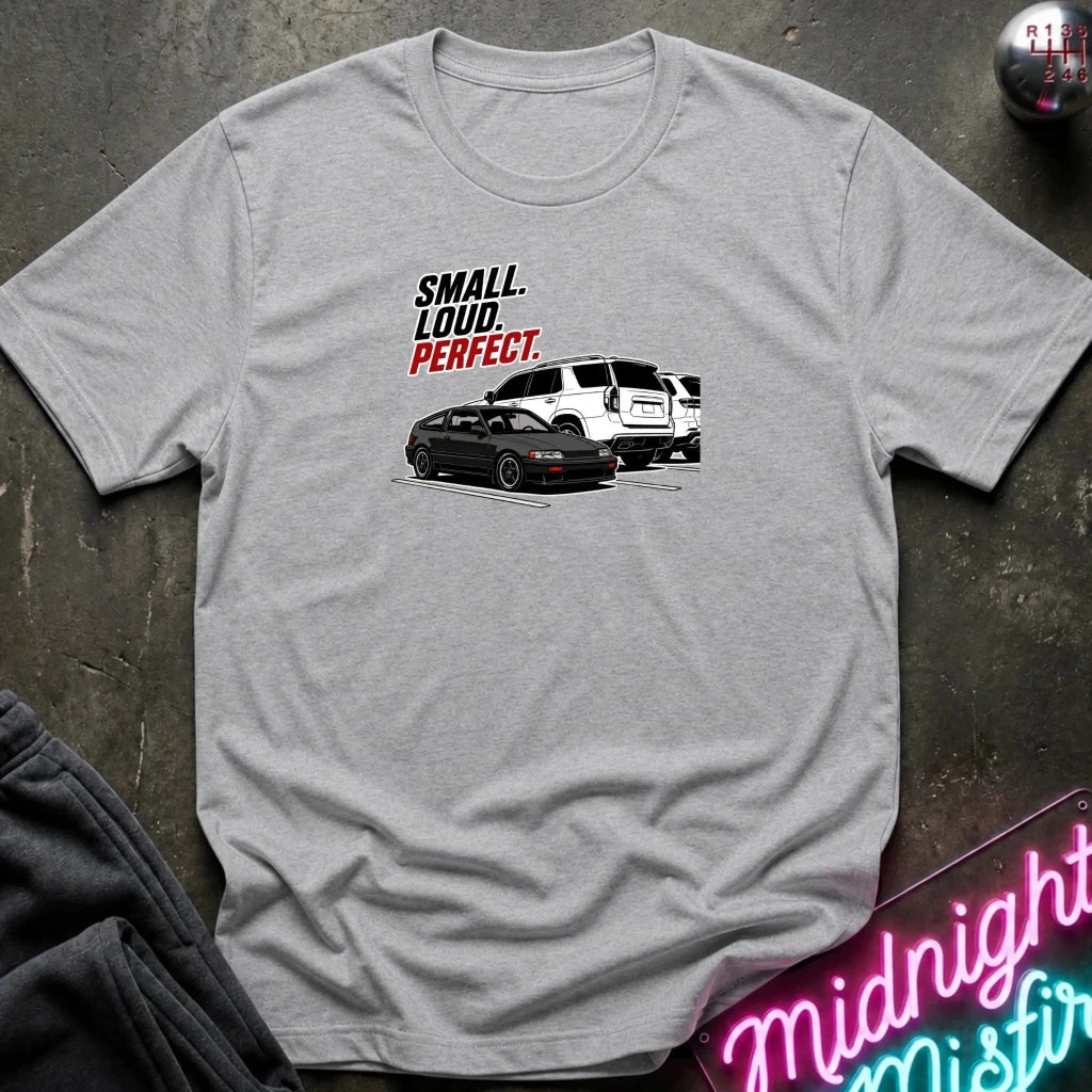 grey  short-sleeve graphic t-shirt laid flat on a dark textured surface. The graphic features the text 'SMALL louD PERFECT.