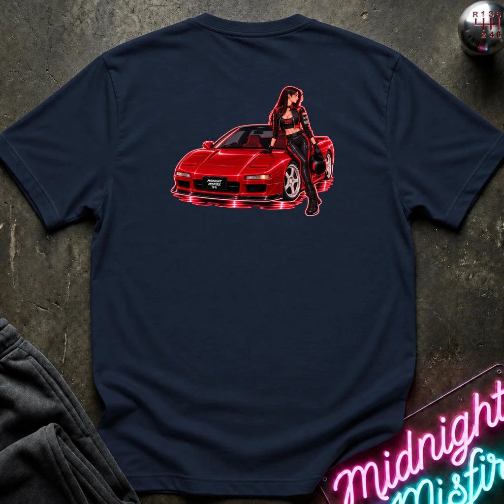 A navy blue t-shirt laid flat on a dark textured surface, featuring a graphic print of a red sports car with a woman leaning on it in red and white neon-style lines.