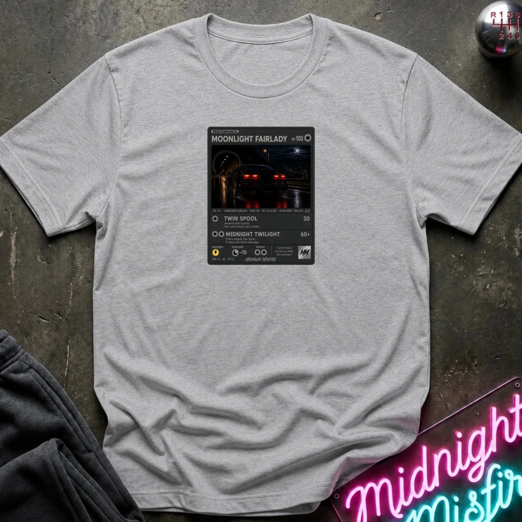 grey crewneck t-shirt laid flat on a dark textured surface, featuring a graphic print of vintage card and a car.