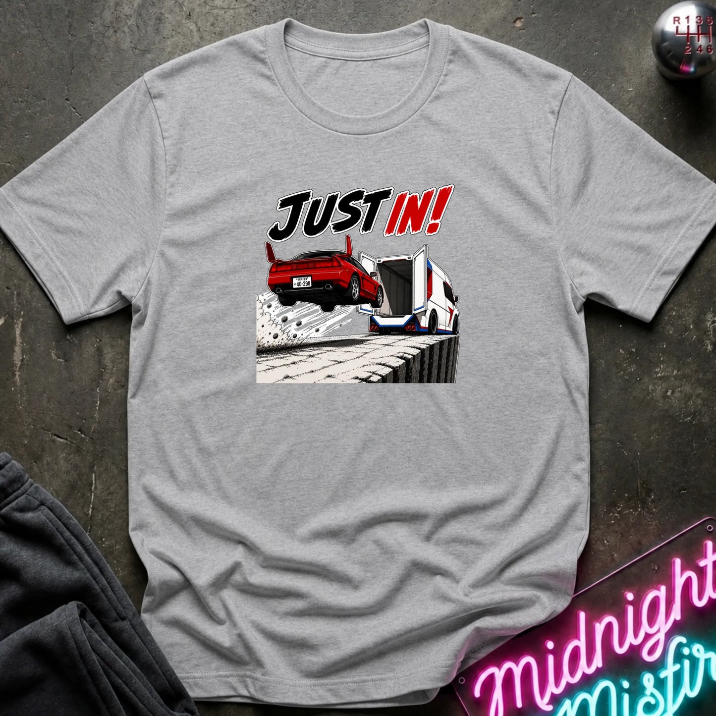 A heather gray short-sleeved t-shirt  that has a red car jumping into back of another machine.