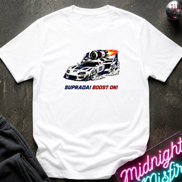 A white short-sleeve t-shirt laid flat on a dark textured surface, featuring a graphic of a white and blue race car with red and orange flames, and the text 'SUPRADA! BOOST ON!' printed below.