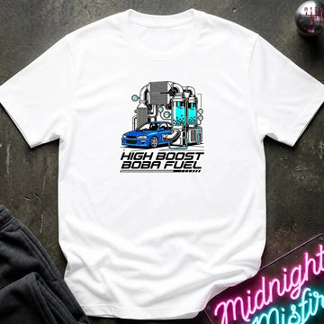 A white short-sleeve graphic t-shirt laid flat on a dark textured surface. The graphic features a blue sports car in front of a glowing teal and gray high-performance machine, with the text 'HIGH BOOST BOBA FUEL' printed below.