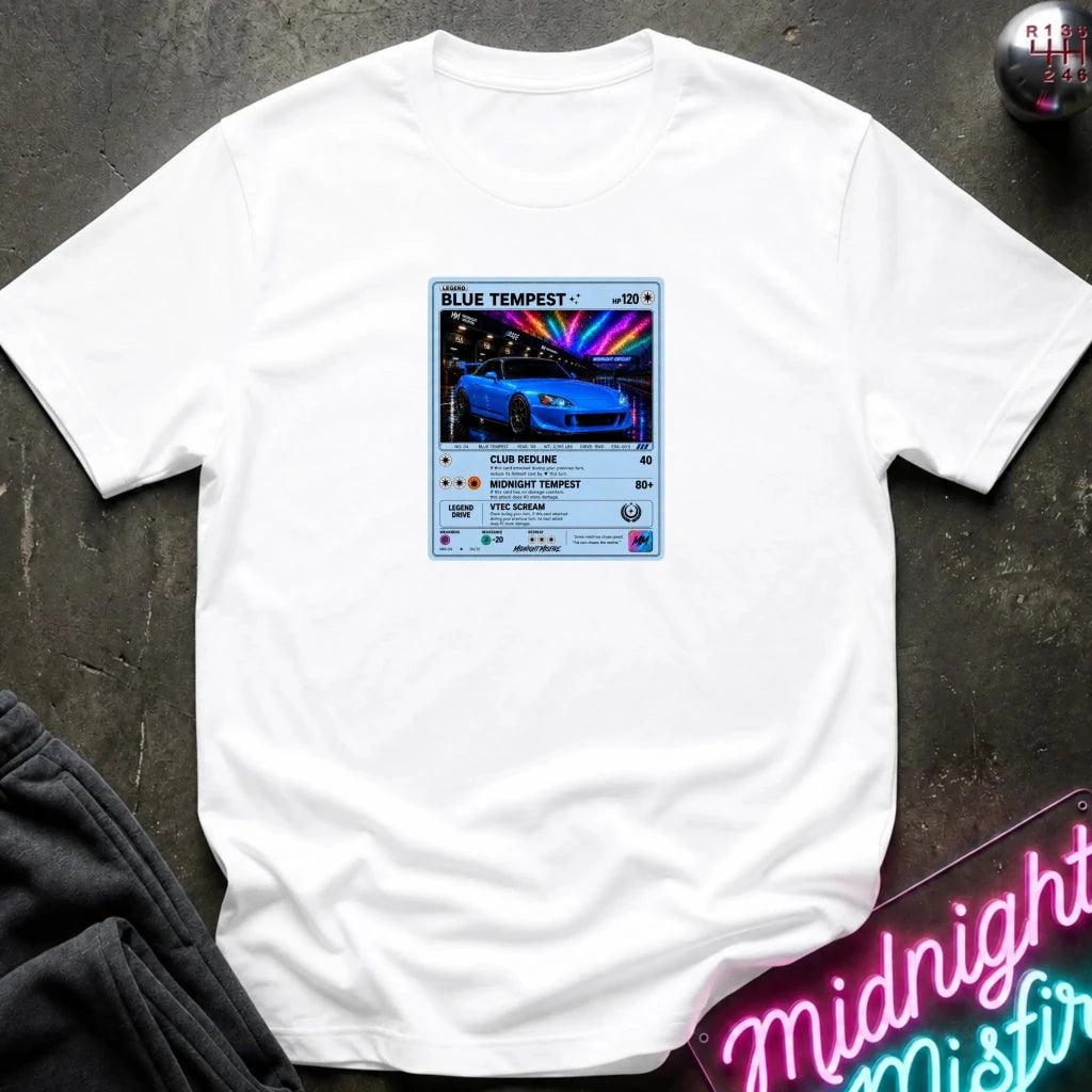 white crewneck t-shirt laid flat on a dark textured surface, featuring a graphic print of vintage card and a car.