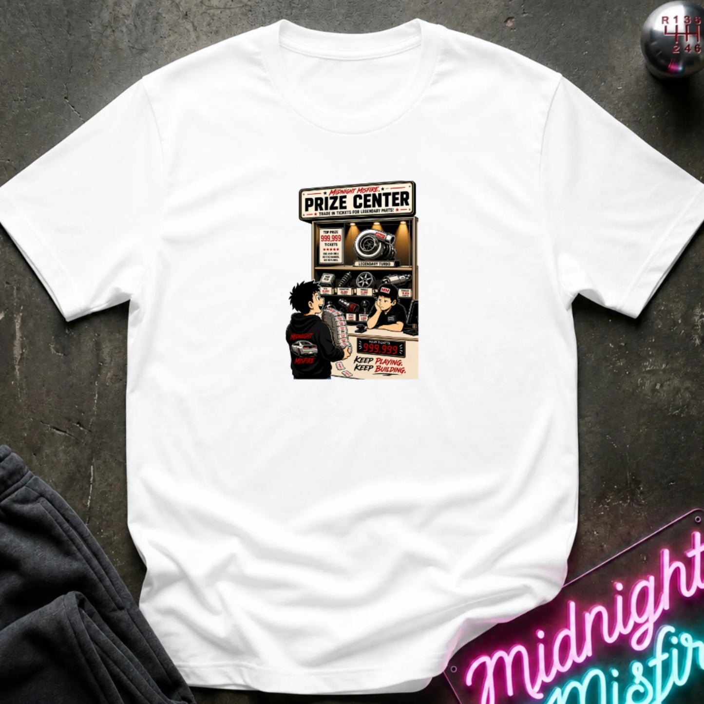 A white short-sleeve crewneck t-shirt laid flat on a dark textured surface, featuring a central graphic print of a prize center for car parts. 