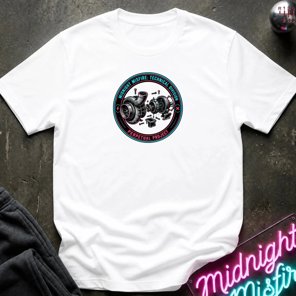 A white short-sleeve crewneck t-shirt laid flat on a dark textured surface. The center of the shirt features a circular graphic with a black and silver turbocharger illustration and red and teal text reading 