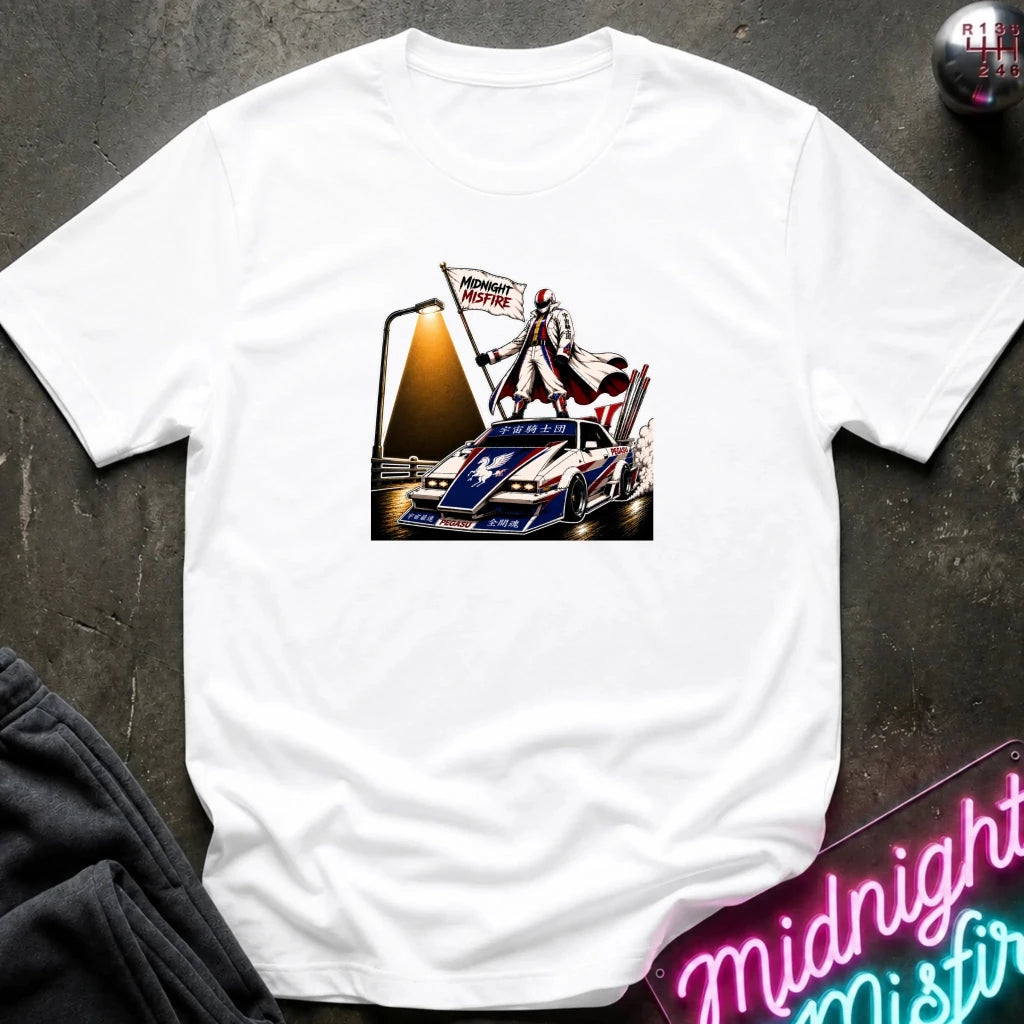 A white short-sleeve t-shirt laid flat on a dark textured surface, featuring a detailed graphic print of a vintage race car with a driver and a 'Midnite Misfire' flag. 