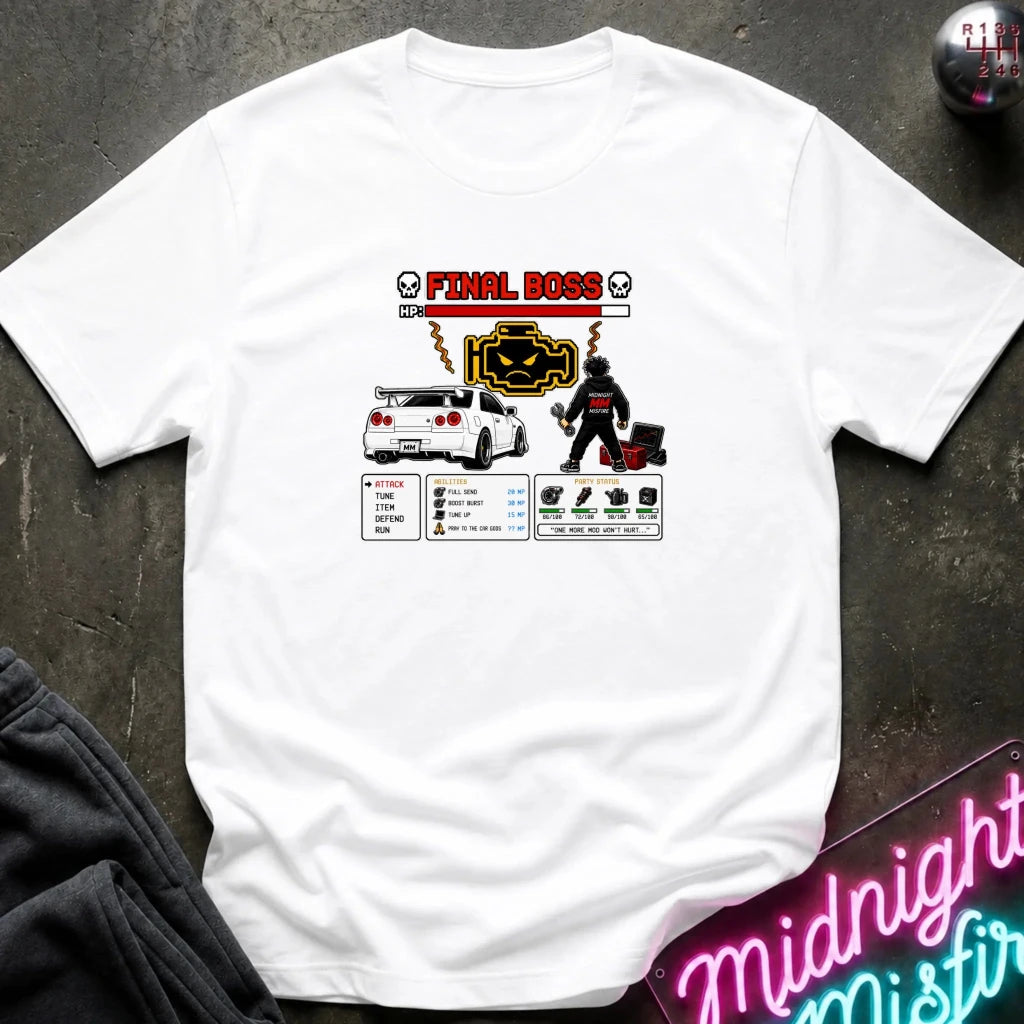 A white short-sleeve graphic t-shirt laid flat on a dark textured surface. The graphic features a red and black 'FINAL BOSS' text design with a car, a character, and various stats.
