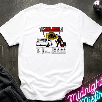 A white short-sleeve graphic t-shirt laid flat on a dark textured surface. The graphic features a red and black 'FINAL BOSS' text design with a car, a character, and various stats.