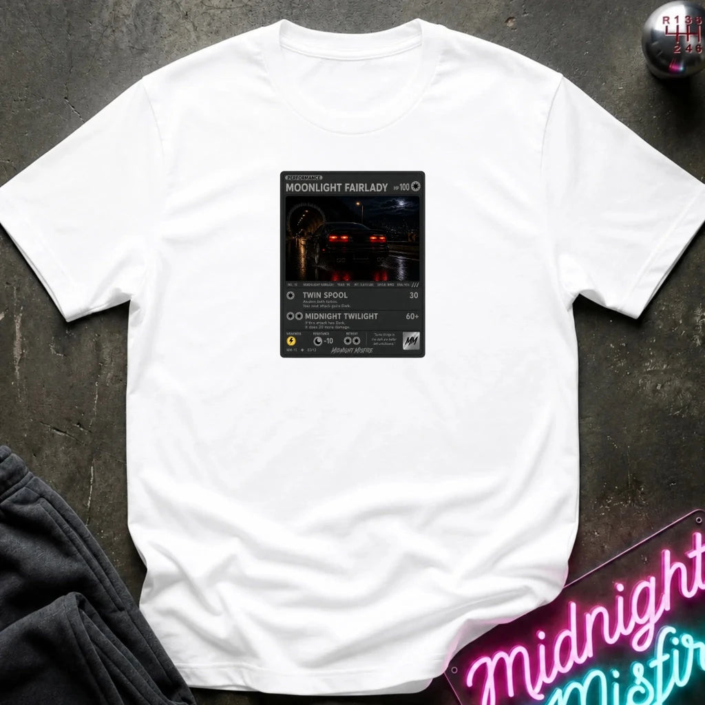 white crewneck t-shirt laid flat on a dark textured surface, featuring a graphic print of vintage card and a car.