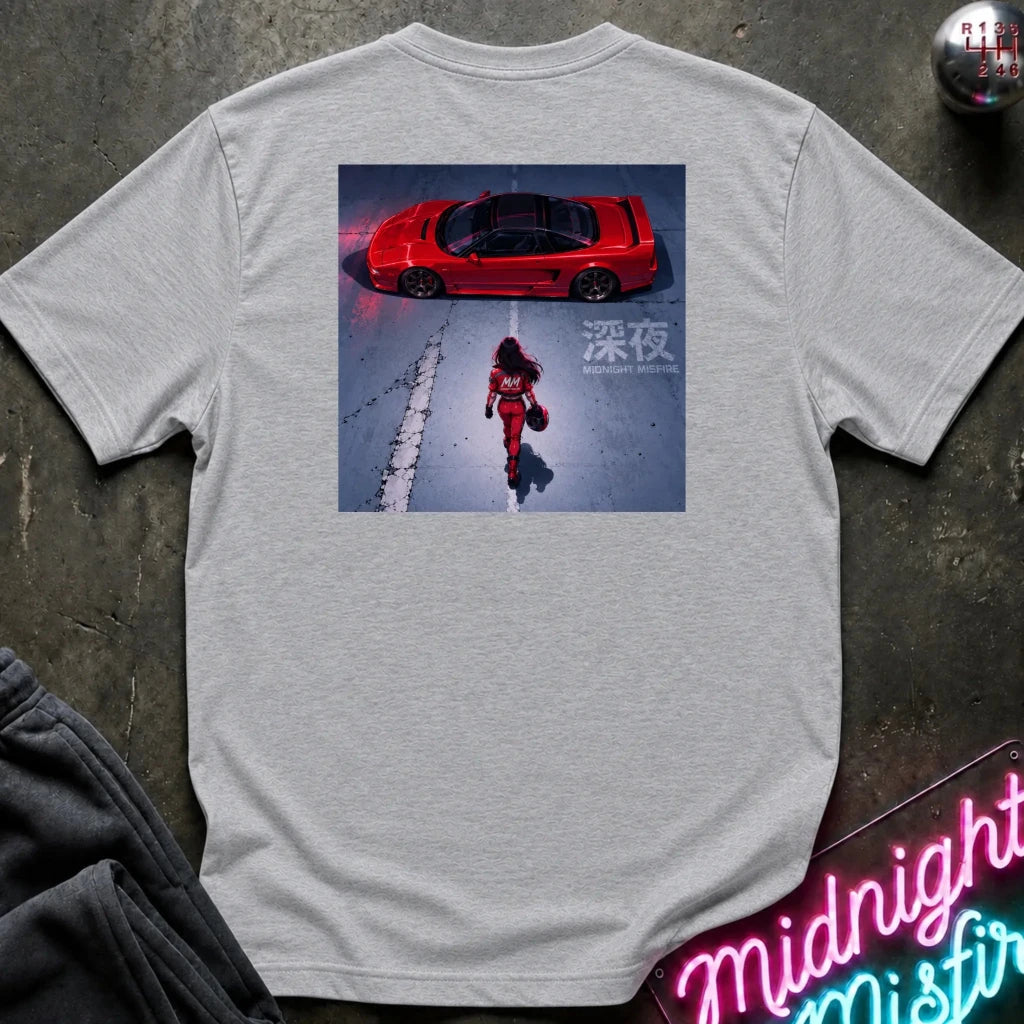 gray short-sleeve t-shirt laid flat on a dark textured surface, featuring a large rectangular graphic print on the back. The graphic shows a red sports car in a snowy scene with a person walking