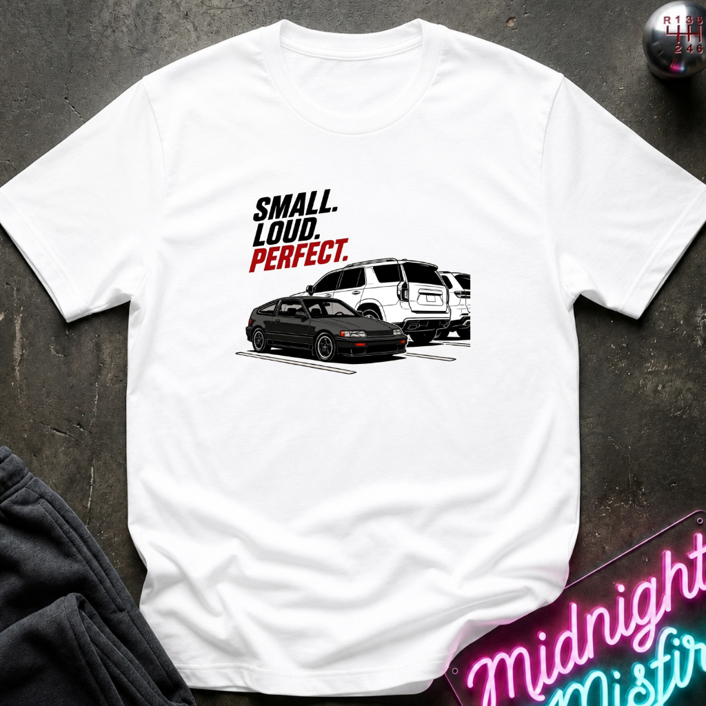 A white short-sleeve graphic T-shirt laid flat on a dark textured surface. The shirt features a printed design with the texts.