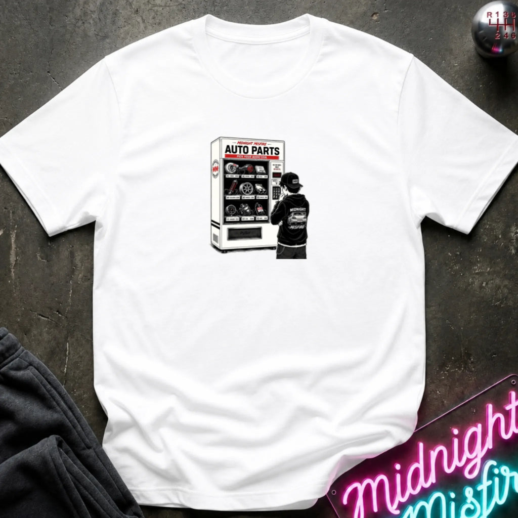 a white  short-sleeve t-shirt laid flat on a dark textured surface, featuring a graphic print of a vending machine and owner deciding.