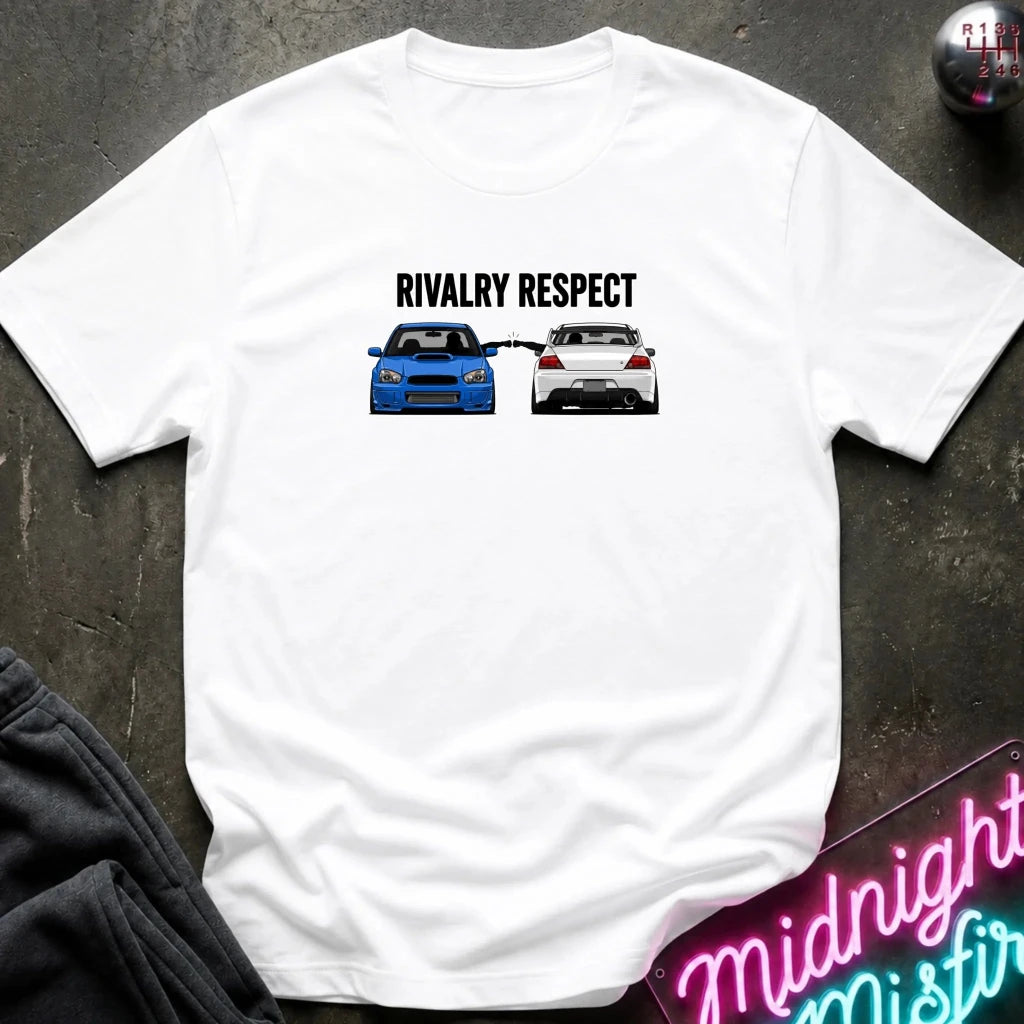 A white graphic t-shirt laid flat on a dark textured surface. The graphic features the text 'RIVALRY RESPECT' above a blue car facing a white car.