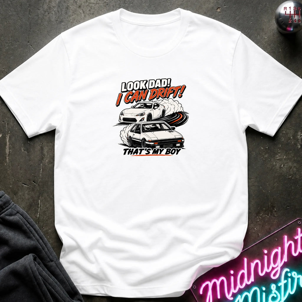 A white short-sleeved t-shirt  that has a cars drifting which are older and newer generations of toyotas.