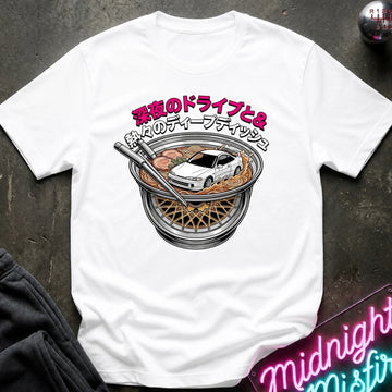 A white short-sleeve graphic T-shirt laid flat on a dark textured surface. The shirt features a large front print of a white sports car driving inside a ramen bowl, with pink and black Japanese text above.