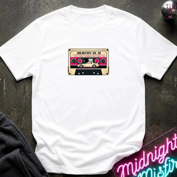 A white crewneck t-shirt laid flat on a dark textured surface, featuring a retro cassette tape graphic on the chest with the text 'JDM MIXTAPE VOL.