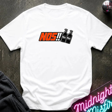 A white short-sleeve t-shirt laid flat on a dark textured surface, featuring a graphic print of the word 'NOS!!' in orange and black next to two black bottles labeled 'NOS'.