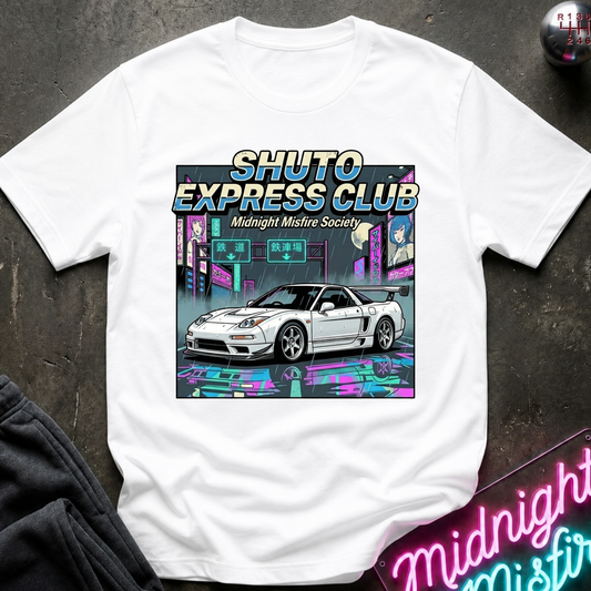 A white short-sleeve graphic T-shirt laid flat on a dark textured surface. The shirt features a colorful retro-futuristic neon-style print with the text 'SHUTO EXPRESS CLUB' and 'Midnight Misfire Society' above an illustration of a white sports car in front of a neon-lit city scene.