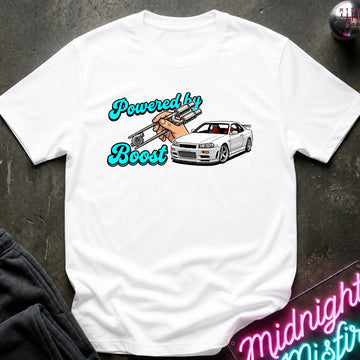 A white graphic t-shirt laid flat on a dark textured surface. The graphic features the text 'Powered by Boost' in a teal cursive font, with a hand holding a silver turbocharger, alongside a white sports car.