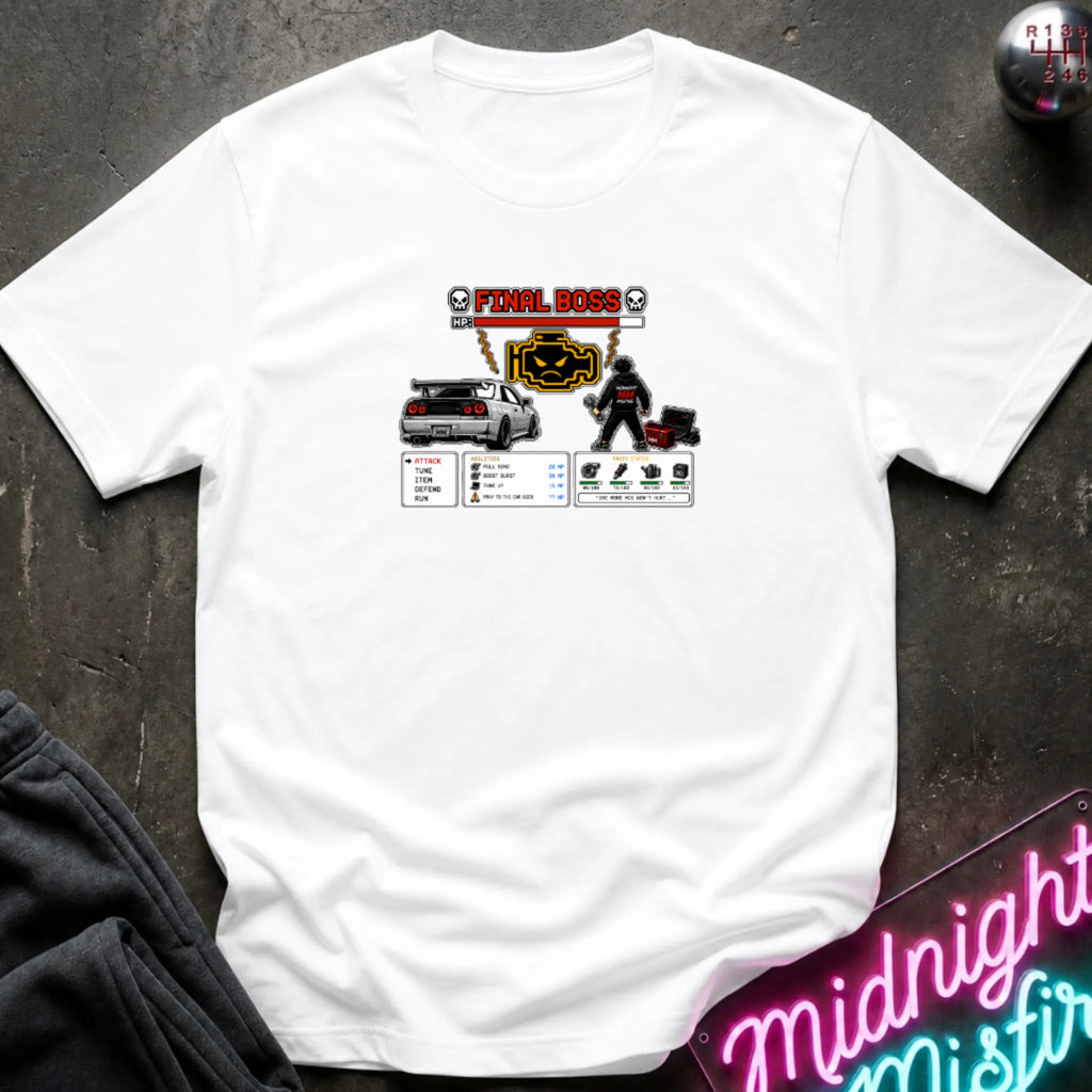A white short-sleeve crewneck t-shirt laid flat on a dark textured surface, featuring a central graphic print of a rpg character and a car. 