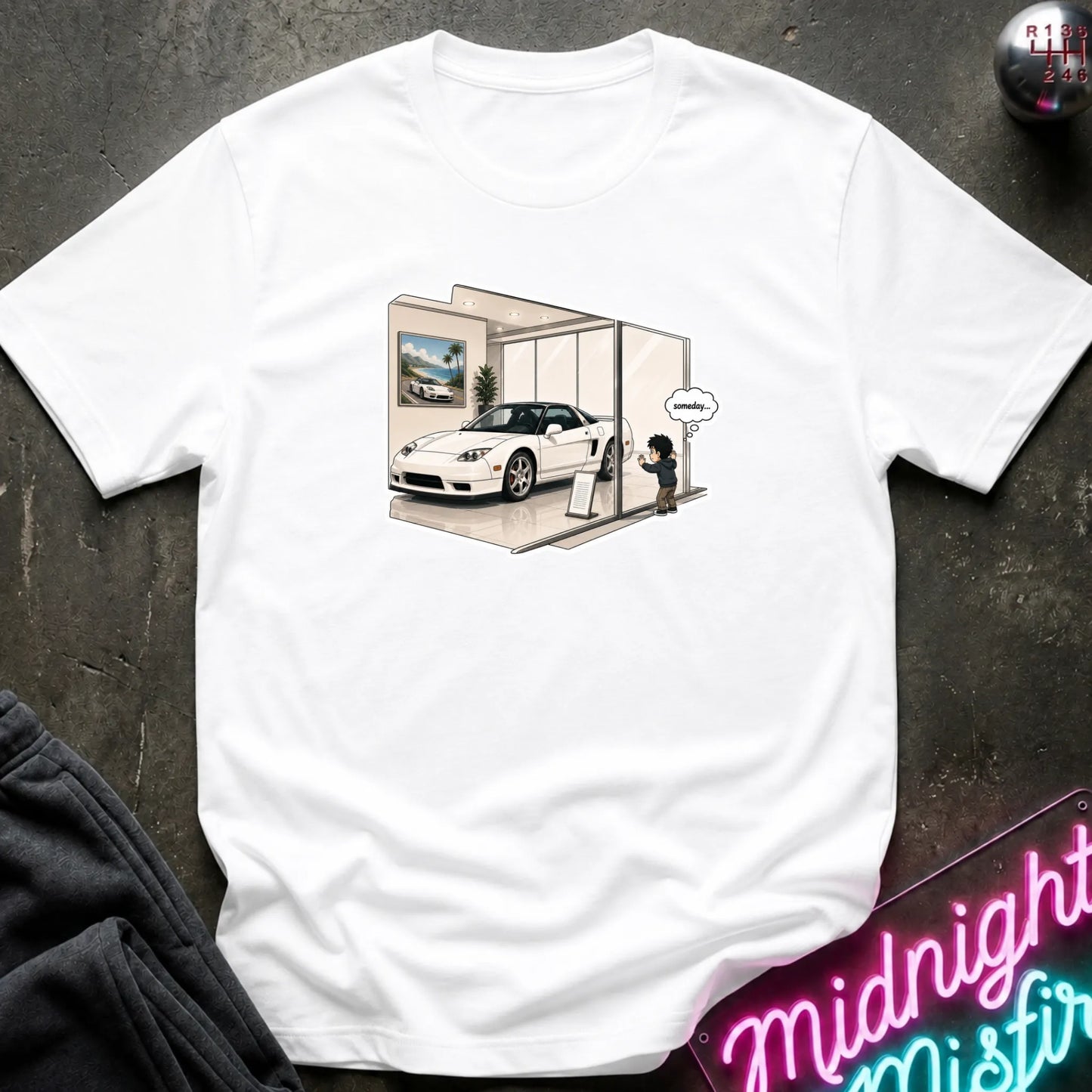 A white short-sleeve crewneck t-shirt with a graphic print of a white sports car inside a showroom, styled flat on a dark textured background with a neon sign and dark pants partially visible.