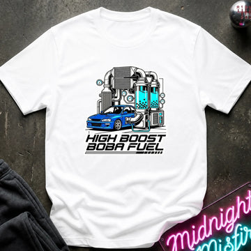 A white short-sleeve t-shirt laid flat on a dark textured surface, featuring a graphic of a blue car connected to a teal and gray high-performance turbo system with the text 'HIGH BOOST BOBA FUEL'.