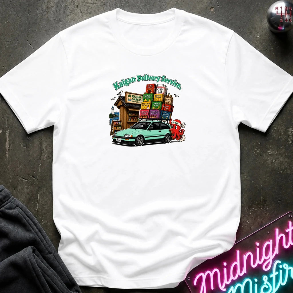 A white short sleeved t-shirt with graphic of a car with snacks on roof with a cartoon character  helping to push.