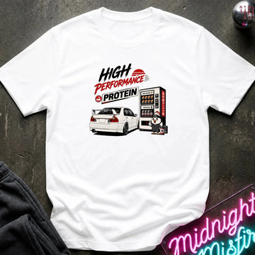 A white short-sleeve graphic T-shirt laid flat on a dark textured surface. The shirt features a printed design with the text 'HIGH PERFORMANCE PROTEIN' above an illustration of a white sports car next to a vending machine.