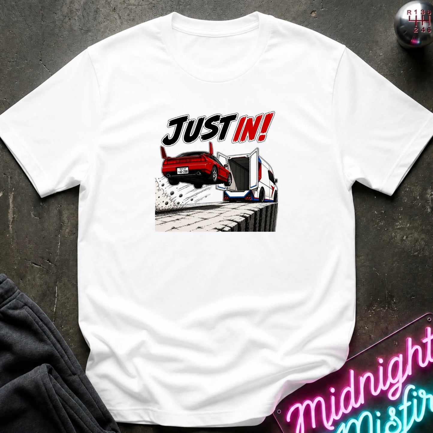 A white short-sleeved t-shirt  that has a red car jumping into back of another machine.