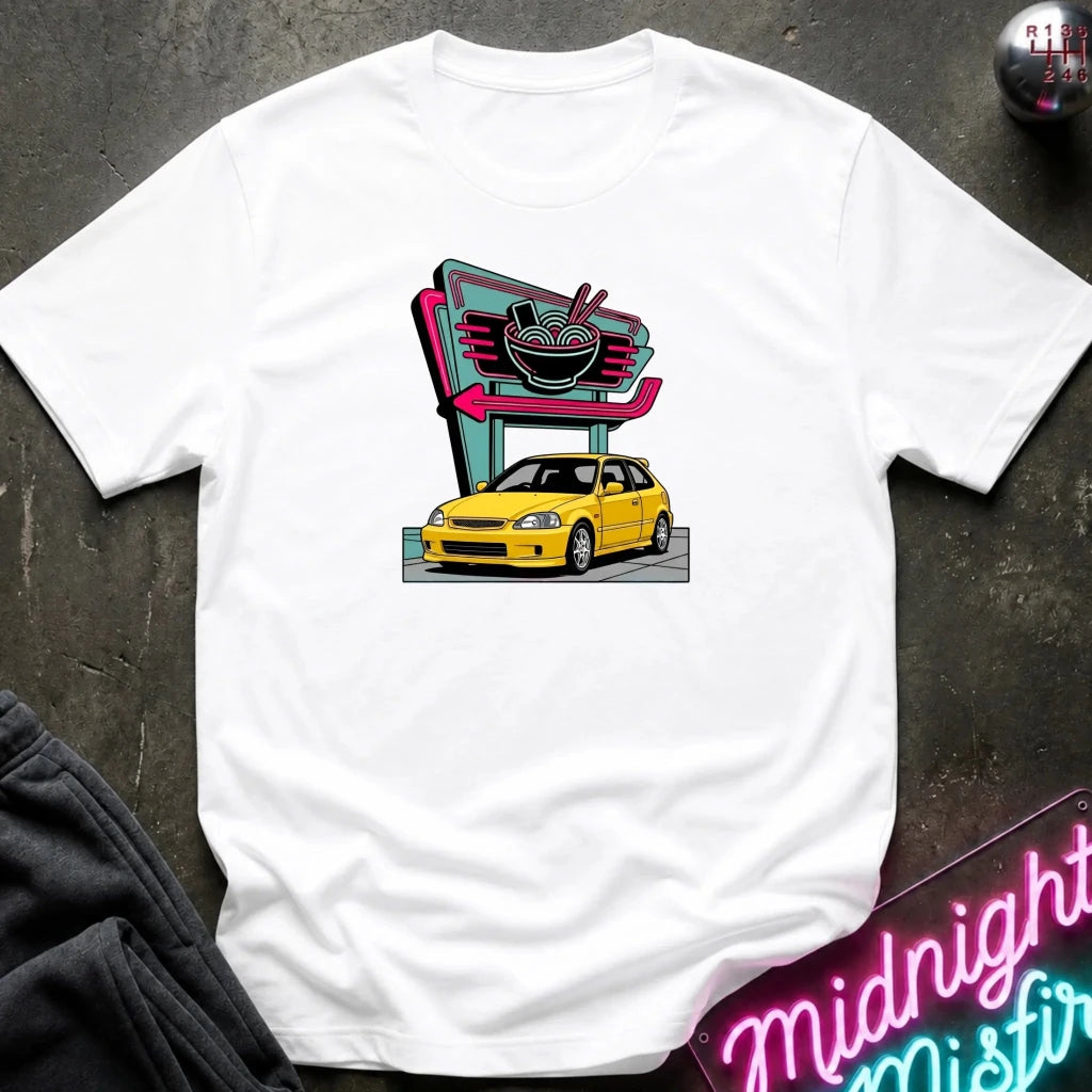 white short-sleeve t-shirt laid flat on a dark textured surface, featuring a retro-style graphic of a yellow hatchback car parked in front of a neon ramen shop sign. 