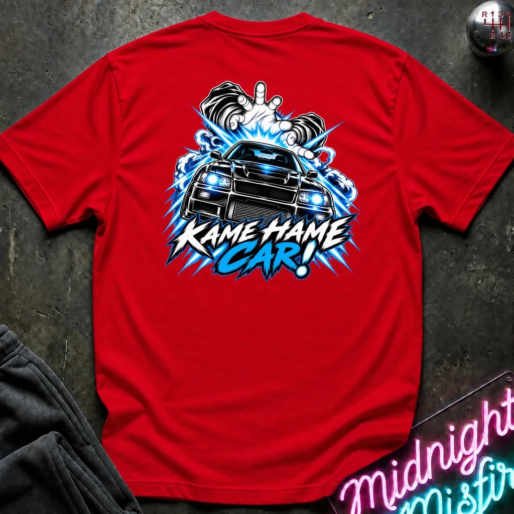 A red short-sleeve t-shirt laid flat on a dark textured surface, featuring a large graphic print on the back with a black car, blue lightning effects, and the text 'KAME HAME CAR!'.