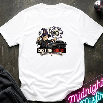 A white short-sleeve graphic T-shirt laid flat on a dark textured surface. The shirt features a colorful cartoon wizard holding a wand next to a black car, with the text 'CASTING BOOST' and smaller text 'Majestic Premium Fuel.
