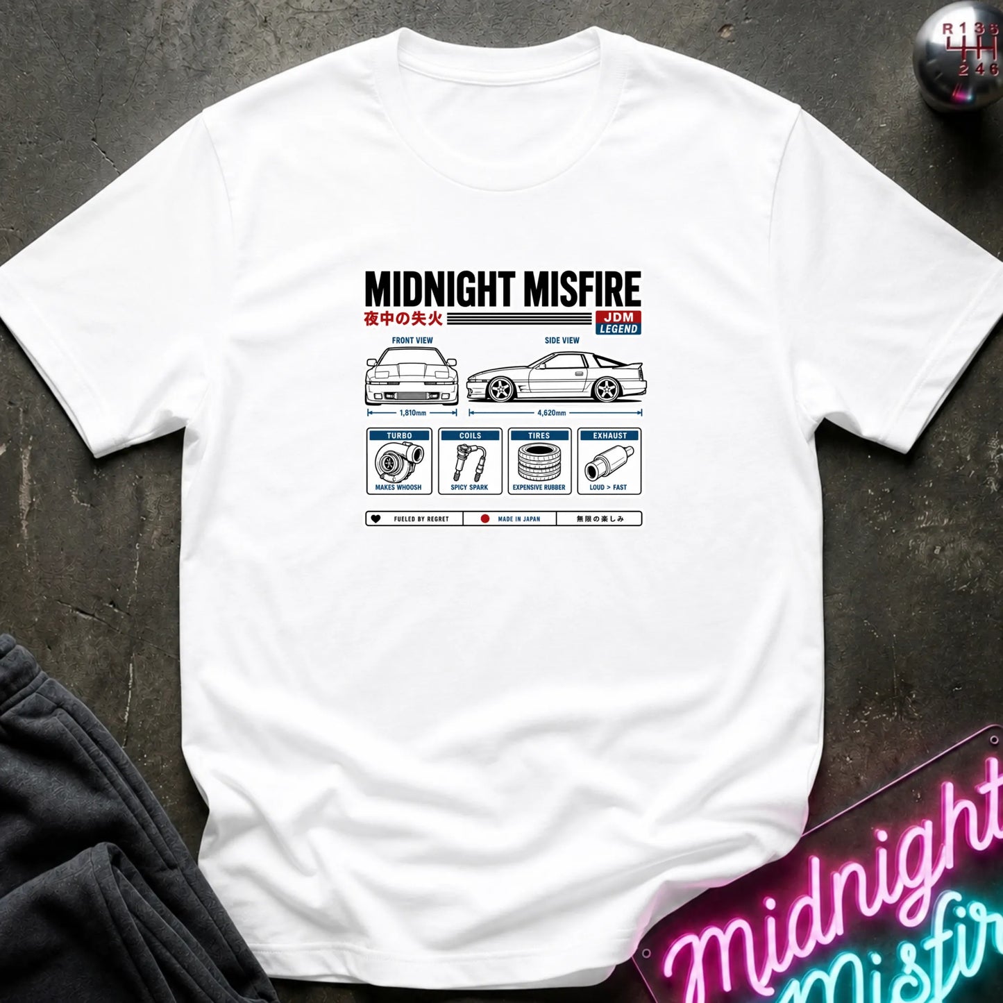 A white short-sleeve t-shirt laid flat on a dark textured surface, featuring a technical schematic graphic of car parts.