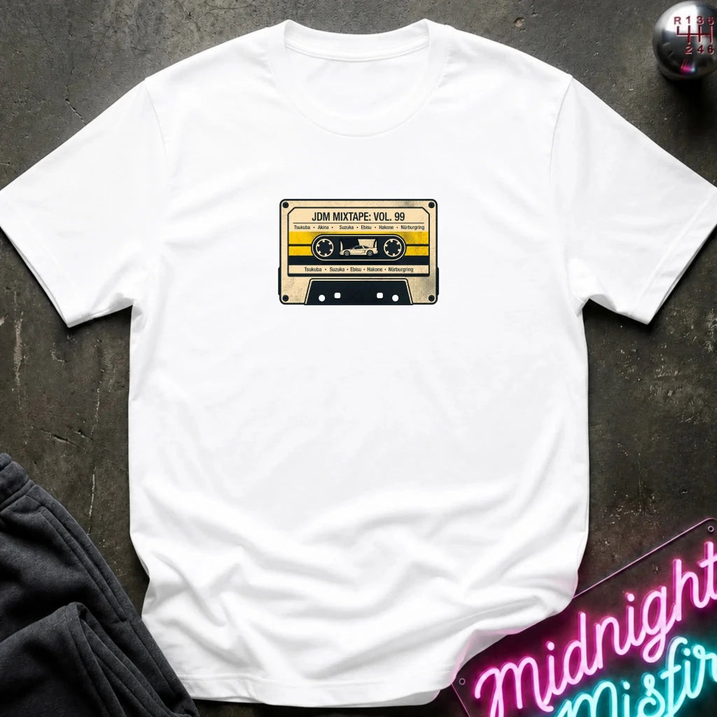 white crewneck t-shirt laid flat on a dark textured surface, featuring a retro cassette tape graphic on the chest with the text 'JDM MIXTAPE VOL.