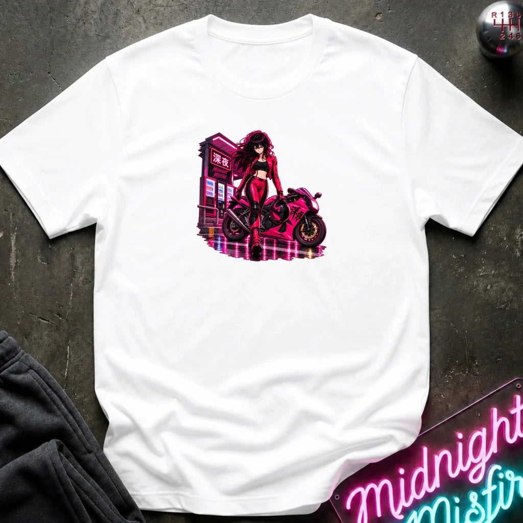 A white short-sleeve crewneck t-shirt laid flat on a dark textured surface, featuring a vibrant pink and red graphic of an anime-style woman with a motorcycle.