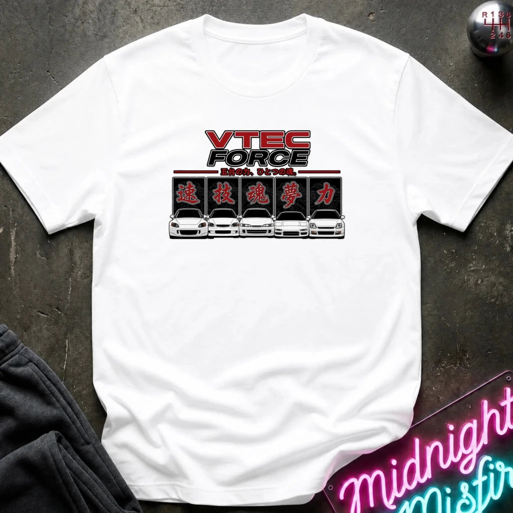 A white short-sleeve t-shirt laid flat on a dark textured surface, featuring a 'VTEC FORCE' graphic print on the chest with red, black, and silver details. Styled flat-lay props include a black sweatshirt in the bottom-left corner and a pink neon sign in the bottom-right corner.
