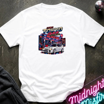 A white short-sleeve crewneck t-shirt featuring a 'Neo Tokyo Gas' graphic with a white sports car, laid flat on a dark textured surface with a neon sign and sweatpants as props.
