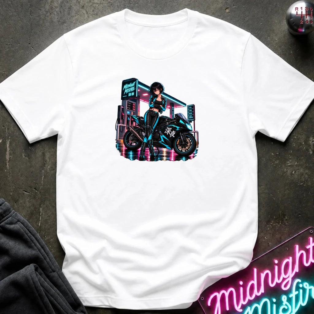 A white short-sleeve t-shirt laid flat on a dark textured surface, featuring a colorful graphic print of an anime-style woman riding a motorcycle in front of a neon sign. 