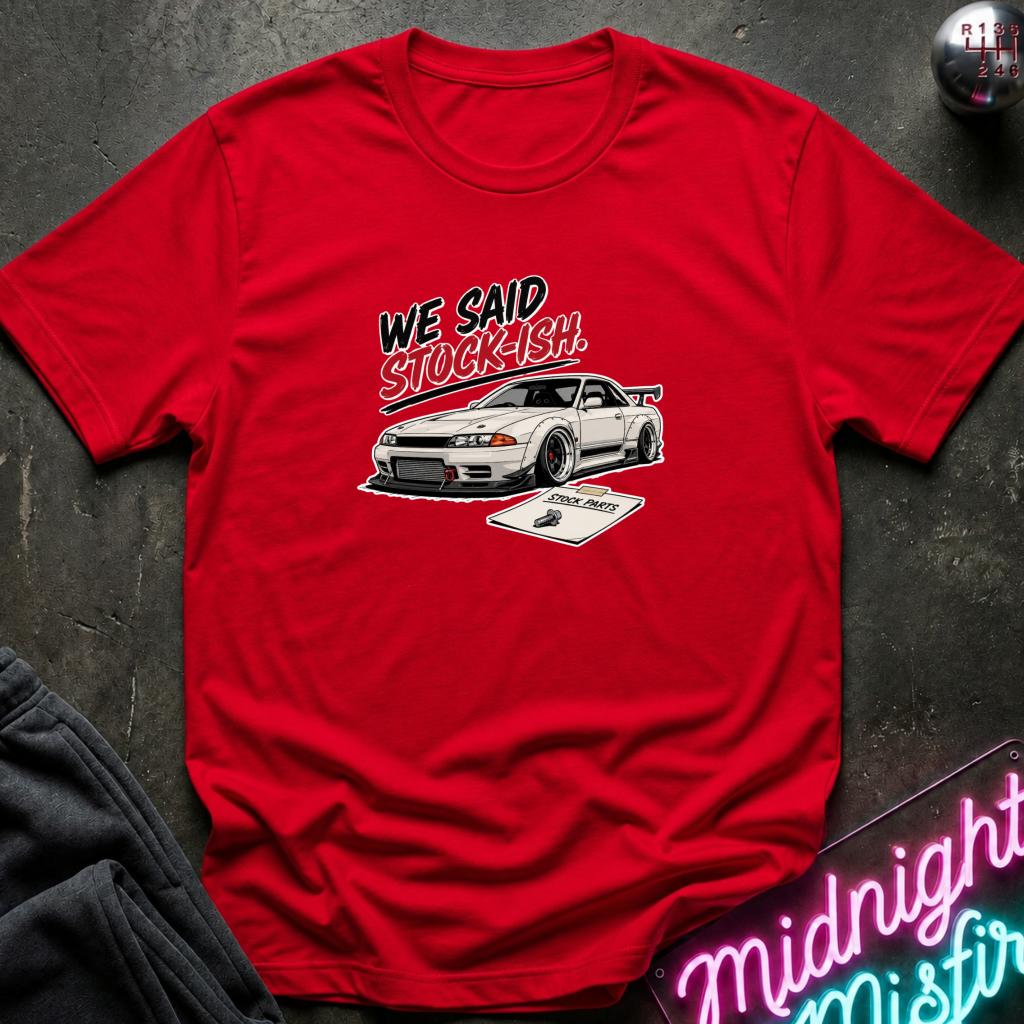 A red short-sleeve graphic T-shirt laid flat on a dark textured surface. The shirt features a white sports car and the text 'WE SAID STOCKISH!' printed on the chest.