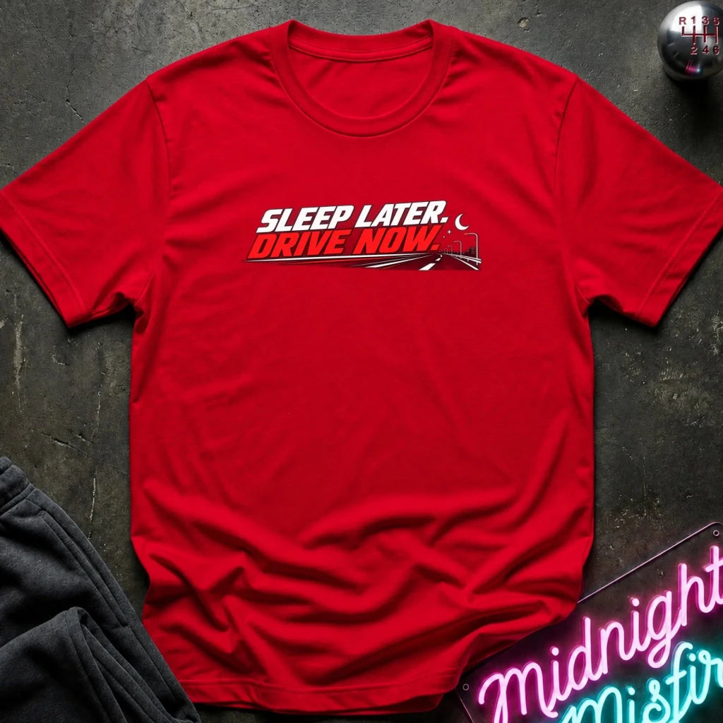 A red short-sleeve crewneck t-shirt with a graphic that reads 'SLEEP LATER. DRIVE NOW.