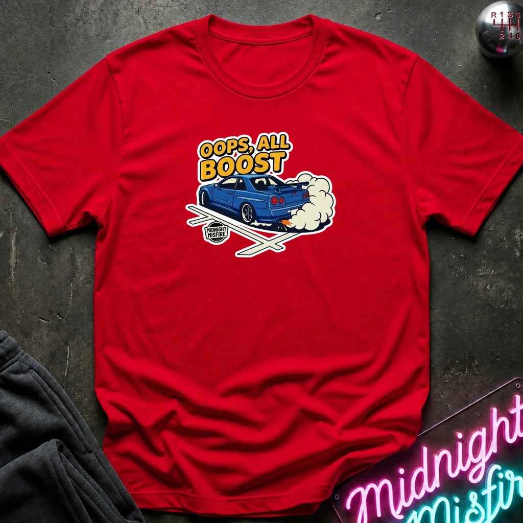 A red short-sleeve t-shirt laid flat on a dark textured surface, featuring a graphic of a blue sports car with exhaust flames and the text 'OOPS, ALL BOOST' in yellow and white.