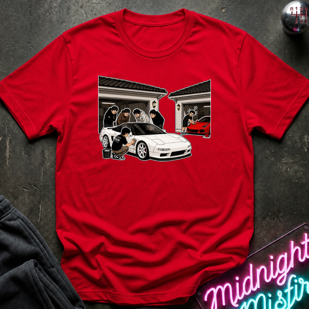 A red short-sleeve crewneck t-shirt featuring a graphic print of a white sports car and a group of men standing in front of a house, laid flat on a dark textured surface.